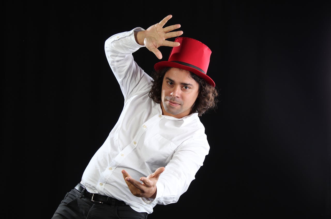 Engaging portrait of a man in a red top hat posing against a black background, capturing a dynamic movement.